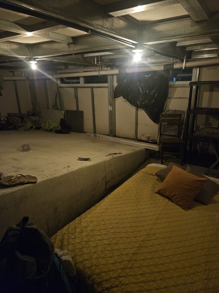 A mattress on a concrete slab in an open alcove at nighttime