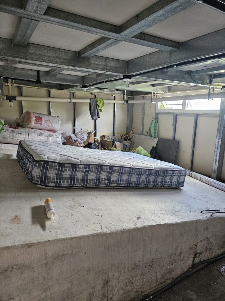 A mattress on a concrete slab in an open alcove